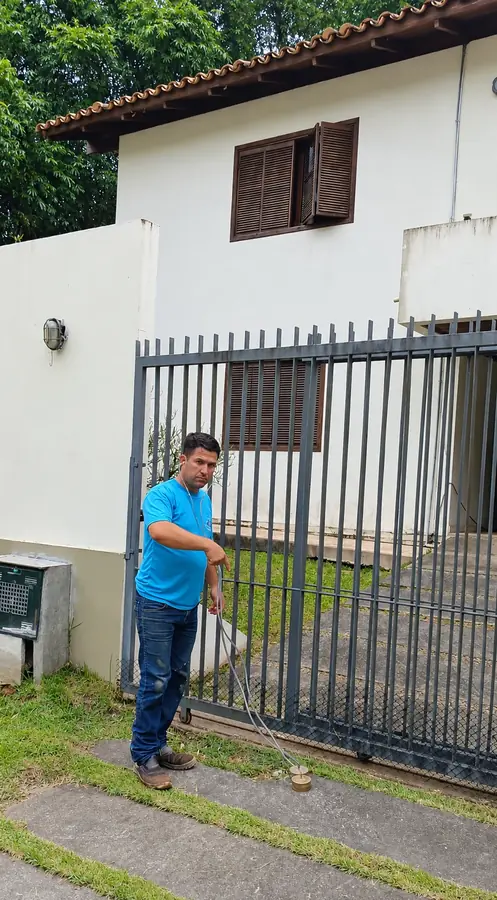 Profissional de camisa azul com ferramenta diante de um portão.