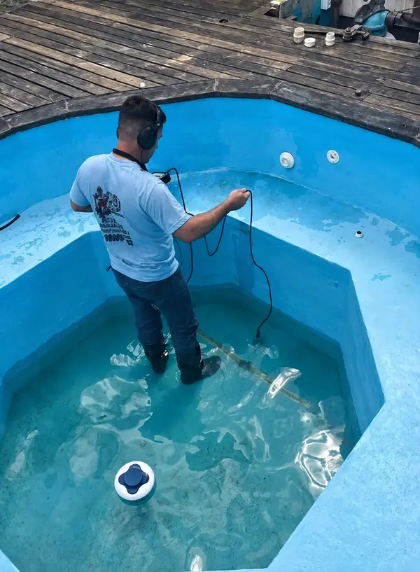 Profissional com ferramenta dentro de uma piscina.