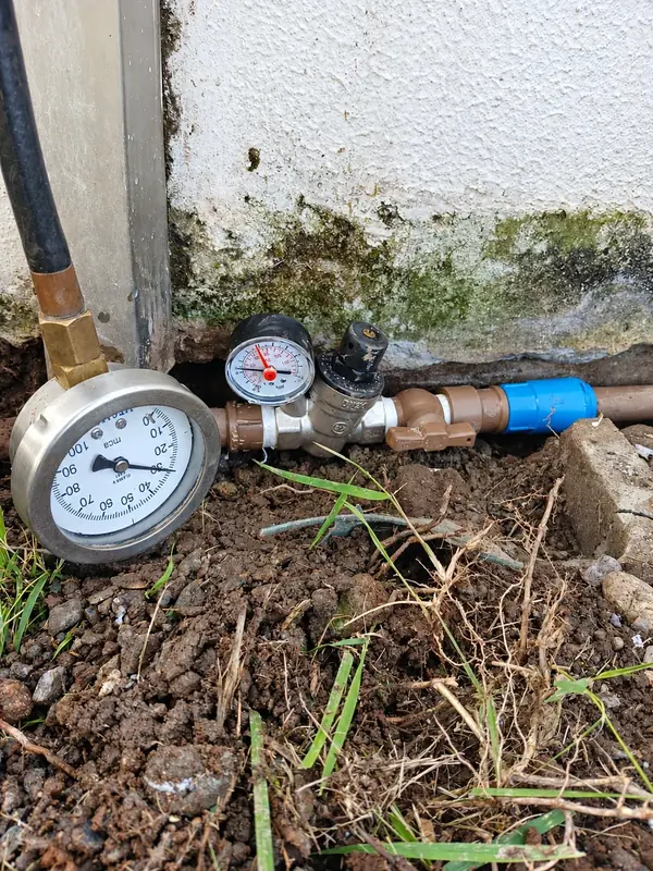 Manômetro conectado a tubulação junto a uma parede.