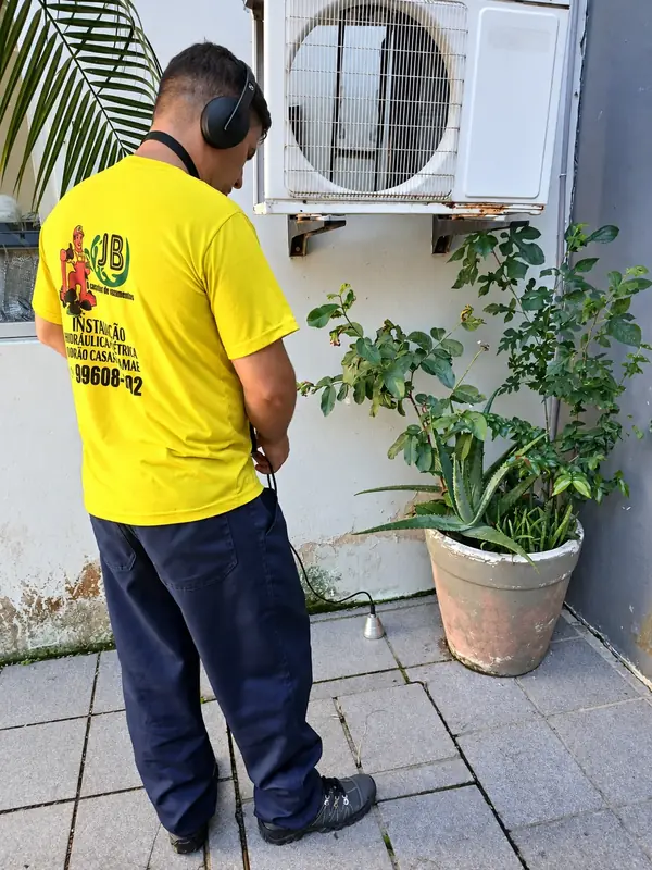 Profissional de camisa amarela trabalhando em área pavimentada.