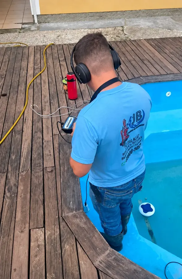 Profissional de camisa azul junto a uma piscina e equipamento vermelho.